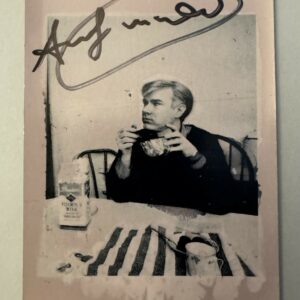 Andy WARHOL (1928-1987), Attribué à. Photographie argentique en noir et blanc, représentant Andy Warhol au déjeuner.   Signé au marqueur. Tampon de la signature « Andy Warhol » au dos de la photographie. Timbre sec en creux Andy Warhol.