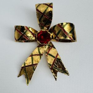 SAINT LAURENT RIVE GAUCHE Broche-pendentif en métal doré, ciselé et strass, figurant un nœud. Signé.