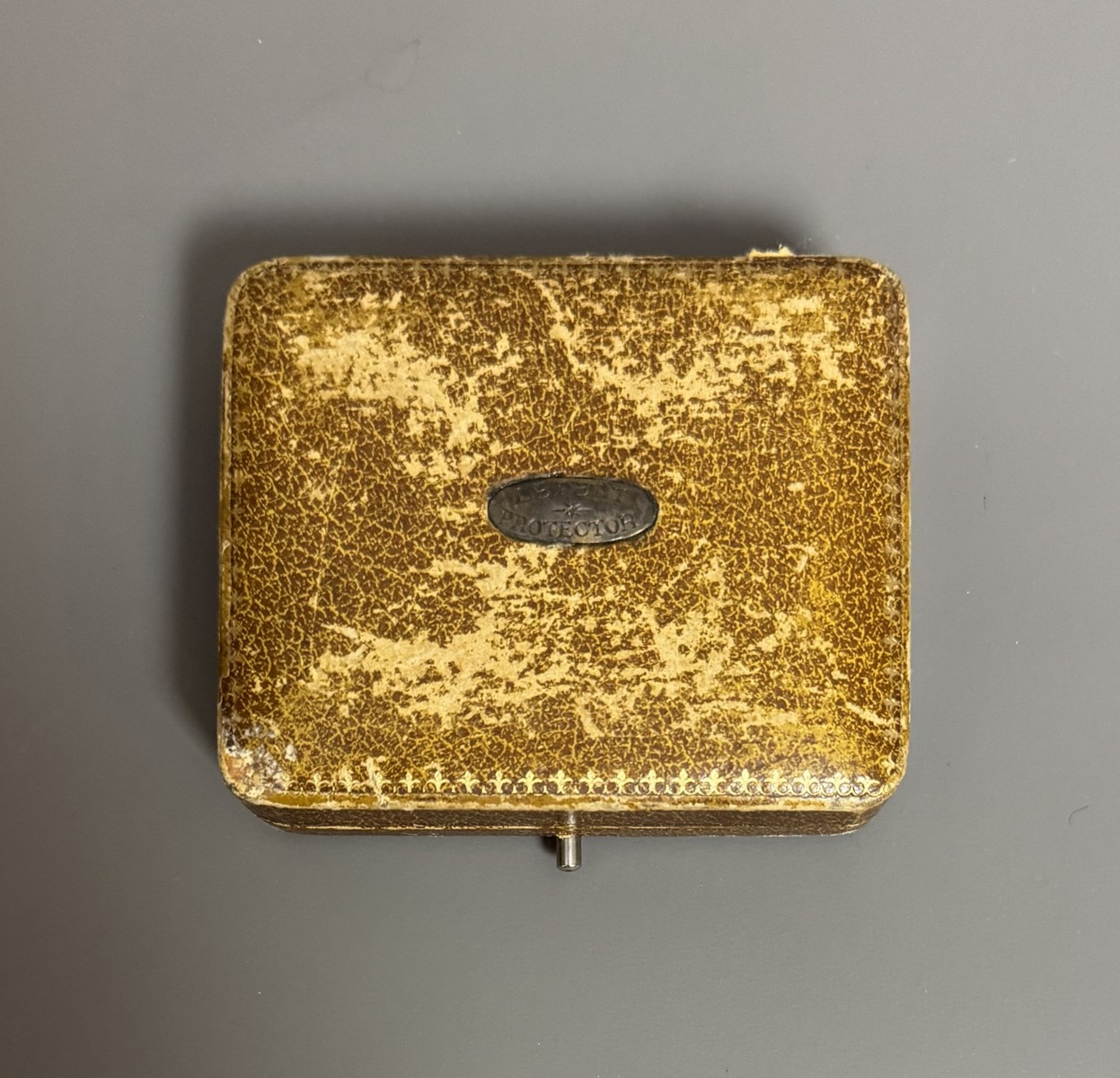 BAGUE RÉVOLVER, « le petit Protector », à broche, 6 coups, calibre 4 mm. Barillet bleu, guilloché sur le bord pour être tourné à la main. Détente latérale. Anneau en maillechort gravé de feuillages et marqué « LE PETIT PROTECTOR » XXe siècle. Dans son coffret en cuir décoré au petit fer, avec plaque en argent gravée « Le petit protector », garni à l’intérieur de velours. Avec sa boîte d’origine (6,7 x 8,2 , 2 cm) , 6 balles de plomb et un tournevis. Complet. - Image 4