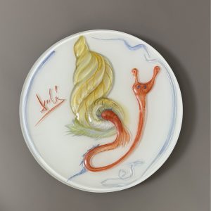 Salvador DALI (1904-1989)  1979. Coupelle en verre opaque blanc, doublage incolore à parois épaisses, moulé et décoré d’une polychromie peinte, représentant un escargot ailé se tortillant hors de sa coquille. Signé « Dali » sur le devant et au revers Exécuté par la manufacture de porcelaine Rosenthal Studio Line. Inscrit au revers « Limitierte Kunstreihen Rosenthal studio-linie Germany 100 Jahre Rosenthal hergestellt im Jubiläumsjahr 1979 Jahresteller in Glas Salvador Dalí 3000/159 ».