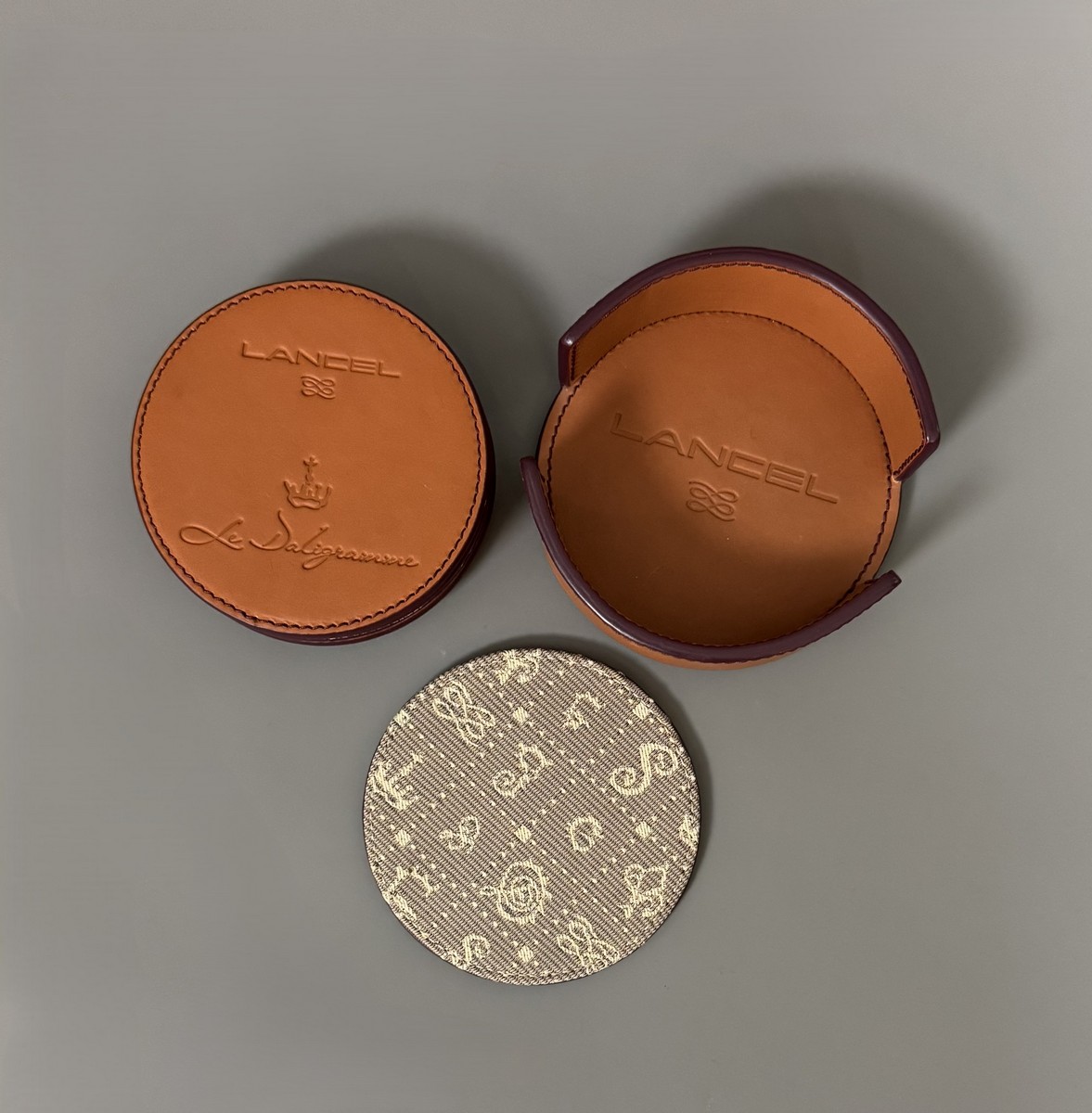 LANCEL & SALVADOR DALI (1904–1989). « Le Daligramme ». Circa 1980. Ensemble de six sous-verres en cuir de vachette et tissu embossé, édités par la maison Lancel, marqués « Le Daligramme ».