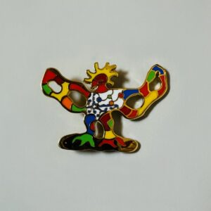 Niki de SAINT PHALLE (1930-2002) d’après.  « Oiseau de feu » Broche-pendentif en métal doré et émail polychrome. Signée « Niki de Saint Phalle au dos ».