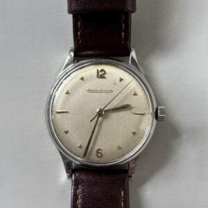 JAEGER LECOULTRE. Montre bracelet, boîtier rond en métal argenté , cadran argenté à index et chiffres arabes, bracelet de cuir noir et boucle ardillon en métal (rapportés).