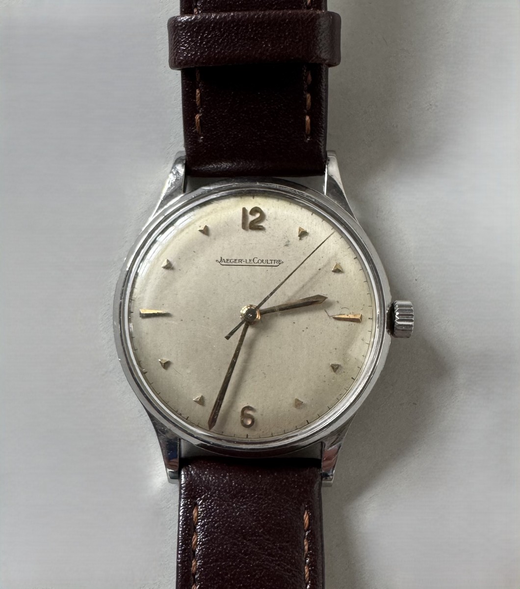JAEGER LECOULTRE. Montre bracelet, boîtier rond en métal argenté , cadran argenté à index et chiffres arabes, bracelet de cuir noir et boucle ardillon en métal (rapportés).