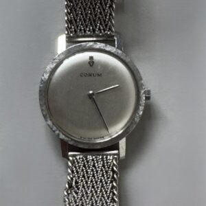CORUM vers 1970, Montre bracelet en or gris, cadran argent, fond clippé. Aiguilles batons. Mouvement mécanique. Bracelet souple en or gris tressé. Poids brut : 38 gr.