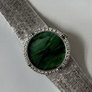 PIAGET. Vers 1970. Montre bracelet pour femme en or blanc 18k (750), lunette sertie de 32 diamants taille brillant et 4 émeraudes,