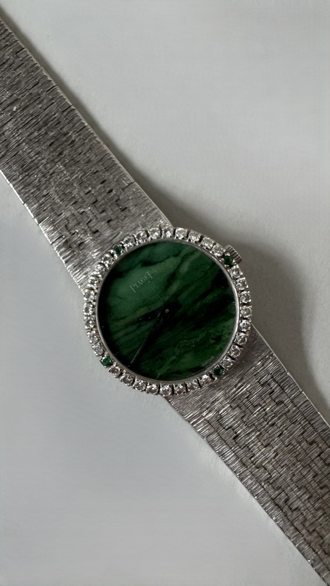 PIAGET. Vers 1970. Montre bracelet pour femme en or blanc 18k (750), lunette sertie de 32 diamants taille brillant et 4 émeraudes,