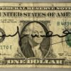 Andy WARHOL (1928-1987), Attribué à. Billet de 1 dollar Américain. Signé « Andy Warhol » au marqueur. Billet datant de 1981 et portant un timbre de 40ct portant le cachet US Air Mail.Cachet de la signature au dos.  Dimensions : 6,6 x 15,7 cm.