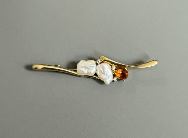 BROCHE en or jaune 18k (750 millièmes) ornée sur la partie centrale de deux perles baroques, petits diamants et un grenat.