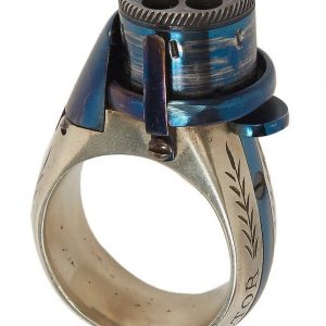 BAGUE RÉVOLVER, « le petit Protector », à broche, 6 coups, calibre 4 mm. Barillet bleu, guilloché sur le bord pour être tourné à la main. Détente latérale. Anneau en maillechort gravé de feuillages et marqué « LE PETIT PROTECTOR » XXe siècle. Dans son coffret en cuir décoré au petit fer, avec plaque en argent gravée « Le petit protector », garni à l’intérieur de velours. Avec sa boîte d’origine (6,7 x 8,2 , 2 cm) , 6 balles de plomb et un tournevis. Complet.
